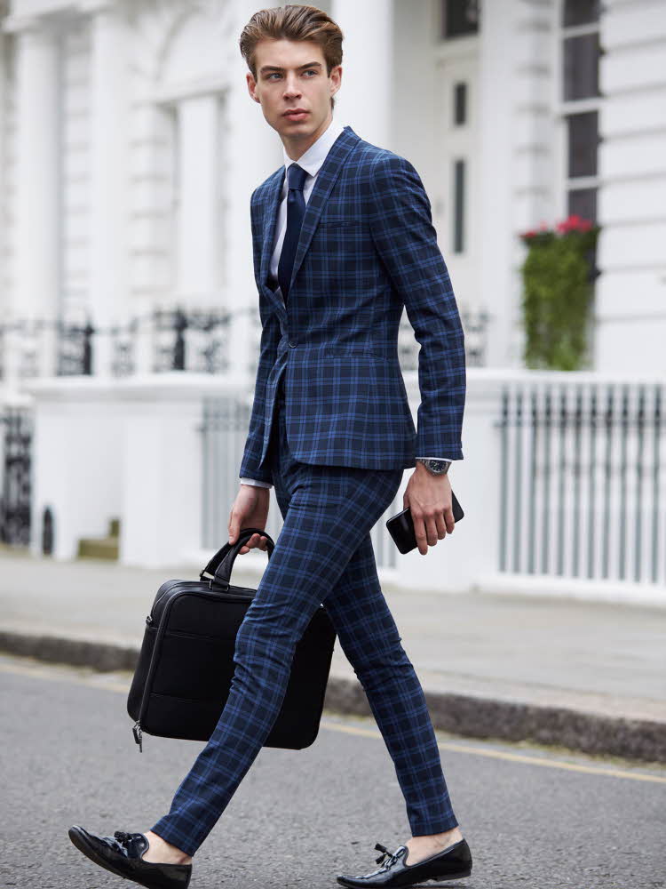 Mann med penny loafers, dress og pcbag går over en vei