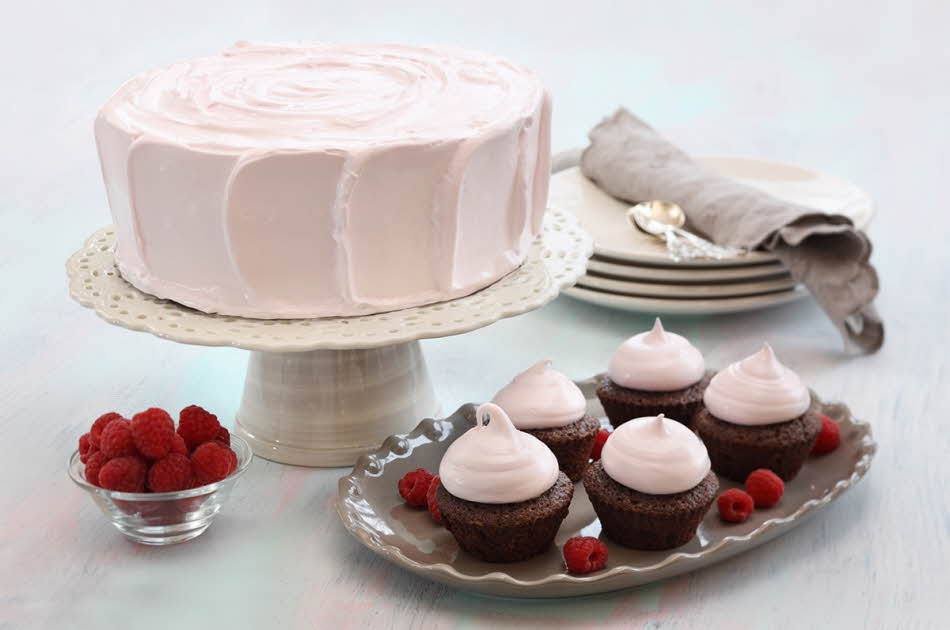 Fem sjokolademuffins med rosa topping ved siden av en rosa kake