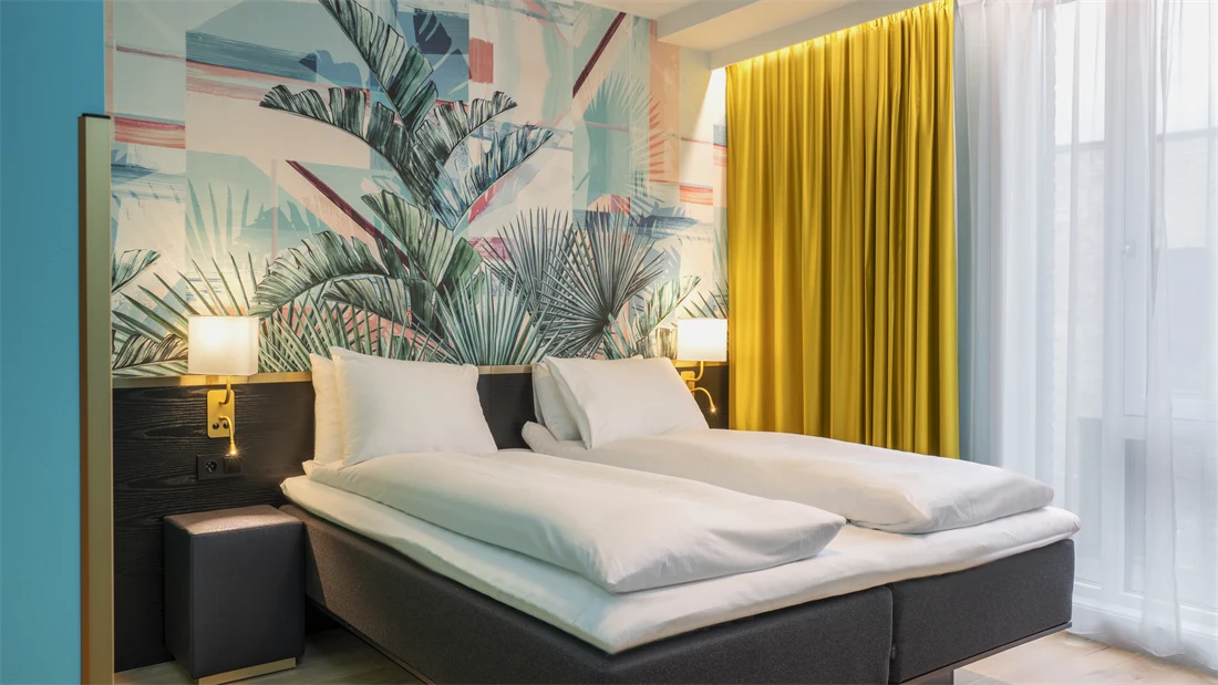 Dobbeltseng og fargerik palmetapet i standard HCP rom på Thon Hotel Storo