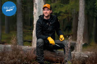 Mann med svart Nordkap Softshell jakke som sitter på en trestokk
