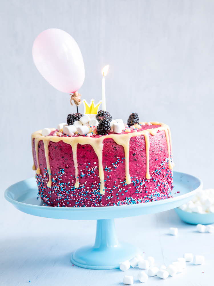 Rosa kake dandert med strøssel, minimarshmellows, bjørnebær, ballong og lys på blått fat