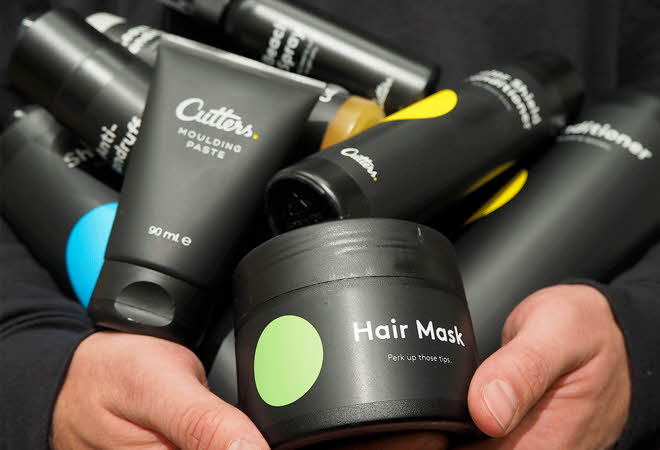 En person som holder diverse hårprodukter fra Cutters