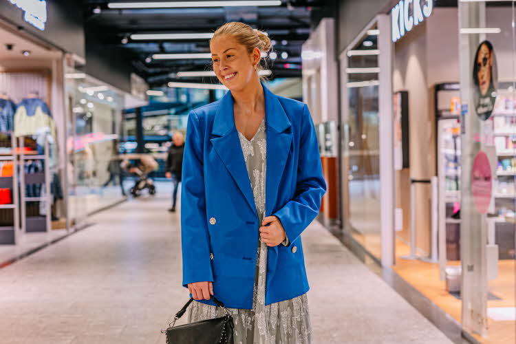 Dame som smiler i blå blazer og sølvkjole