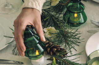 En hånd som plukker opp en juletredekorasjon i glass.