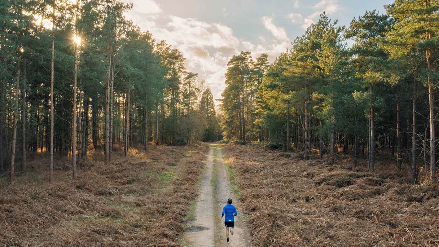 Mann er på joggetur i skogen.