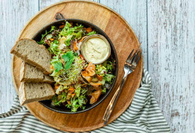 trefat med skål med salat, dressing og skiver til fra baker brun