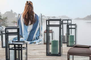 Person på brygge med blå- og hvitstripet teppe.