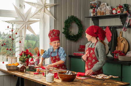 To barn som baker pepperkaker med dekorert kjøkken med julepynt