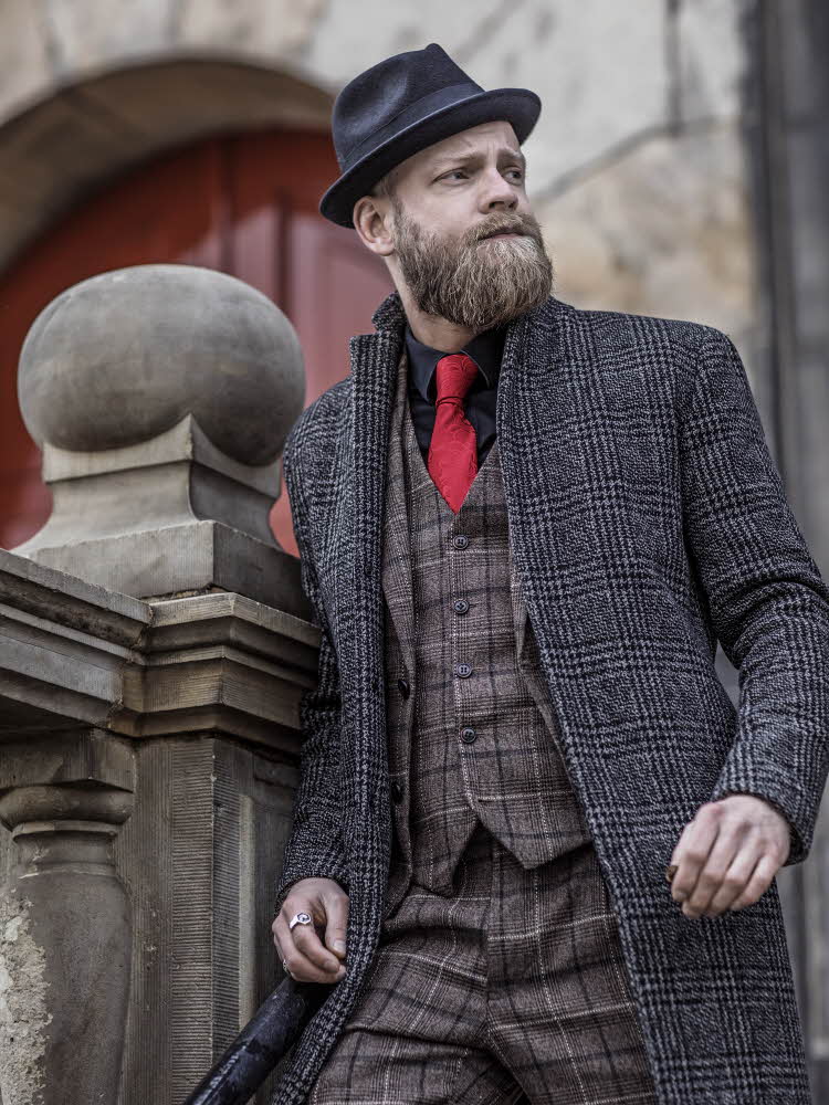Mann som lener seg på et steinrekkverk i rutete dress