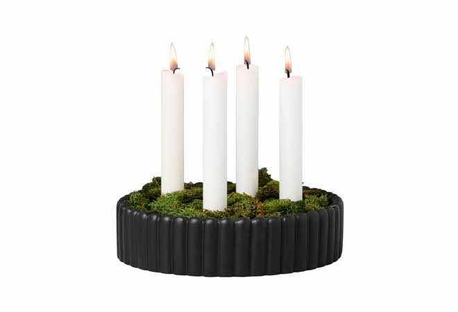 Sort, rund lysestake med fem hvite stearinlys og grønn mose.