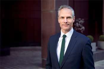 Colin Waddell, daglig leder i CBRE, poserer med dress i et mørkt rom