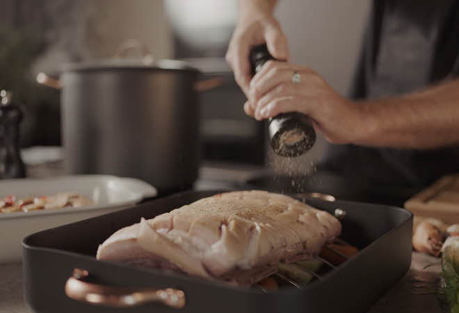 Nærbilde av hendene til en person som krydrer en ribbe som ligger i en form