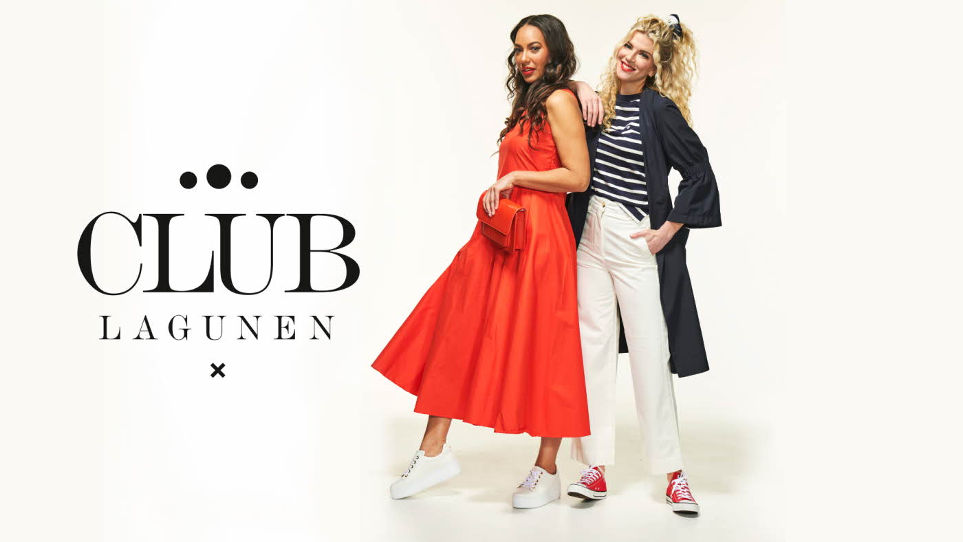 To damer står inntil hverandre, en med rød kjole og veske og en med blå og hvit stripet topp, hvit bukse og blå kåpe. Bakgrunn med Club Lagunen
