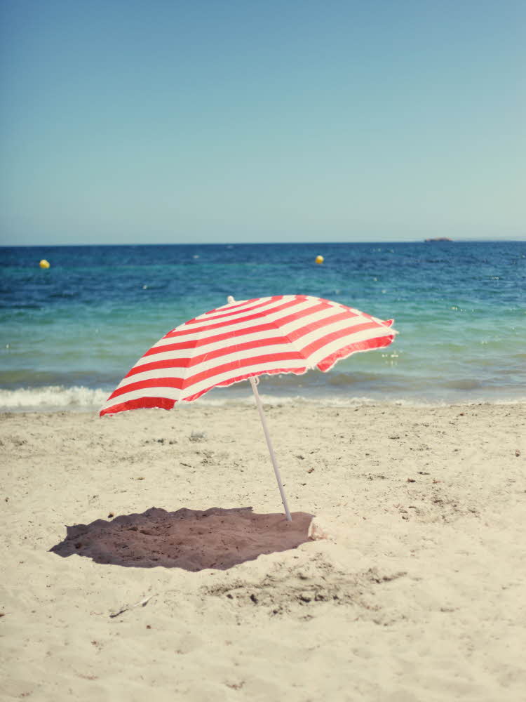 Stripete parasoll på sandstrand Pia og en god venninne som ligger i hver sin hengekøye ved et vann