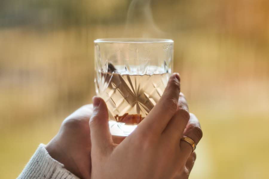 Hånd som holder et glass med varm drikke 