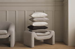 Moderne interiør med beige lenestol og benk med puter.