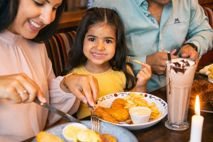 Familie som sitter å spiser middag på restaurant