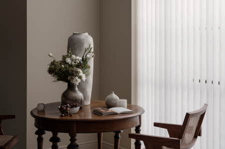 Et bord med en liten vase med blomster og en stor tom vase