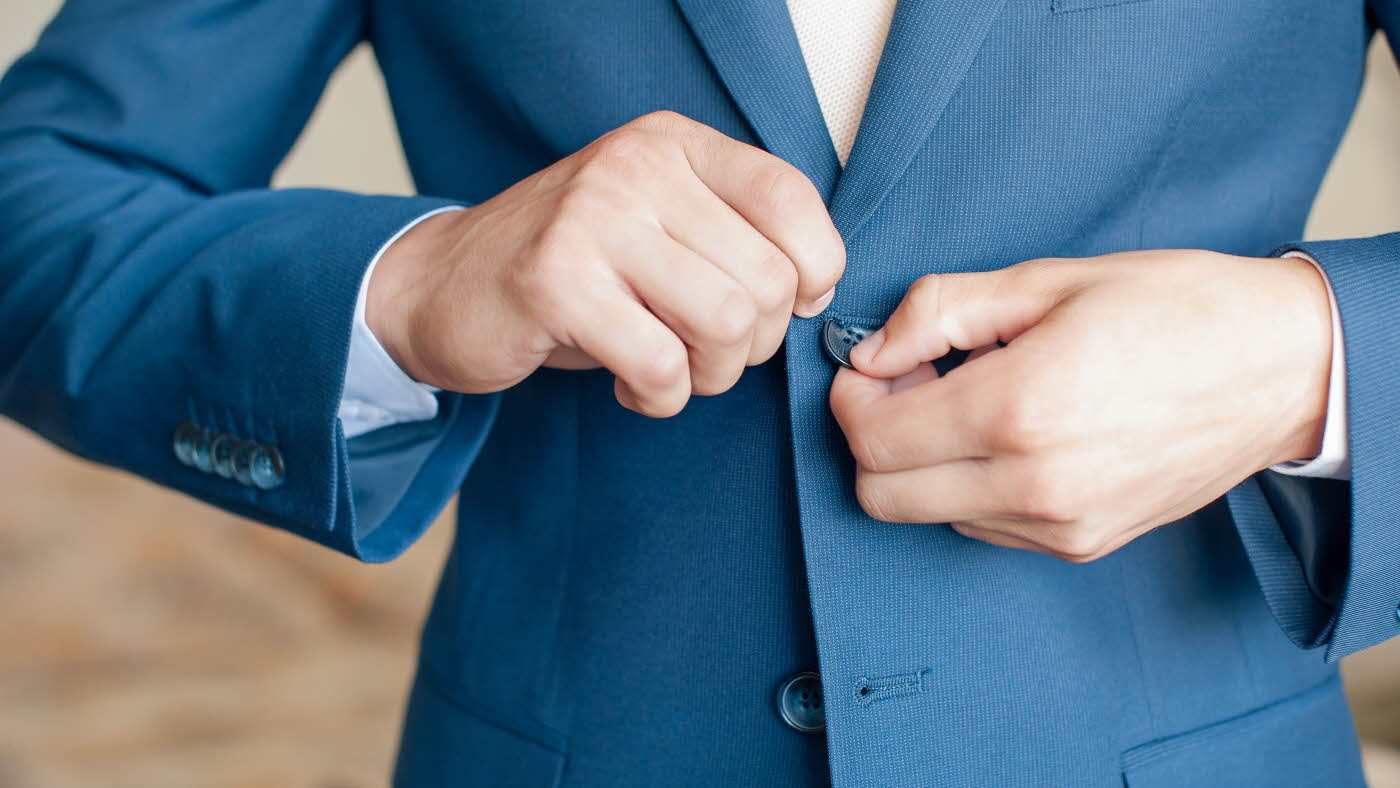 Nærbilde av hender som knepper igjen blazer