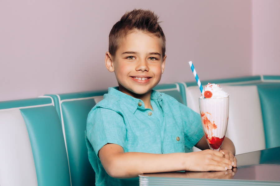 Gutt i turkis skjorte sitter i diner med milkshake foran seg
