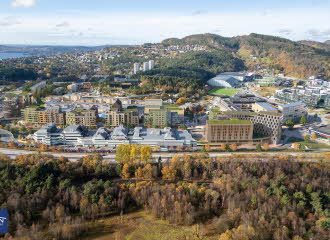 Illustrasjon viser et flyfoto av eksisterende Åsane sentrum, hvor nye planlagte bygninger er tegnet inn i grønt.