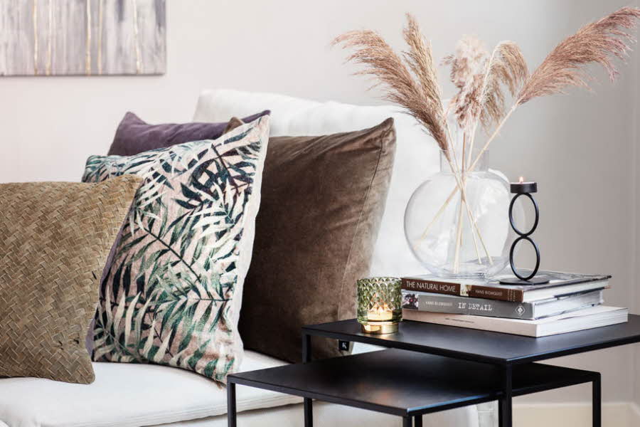 bord med vase, lysestaker og sofa med puter i jordfarger