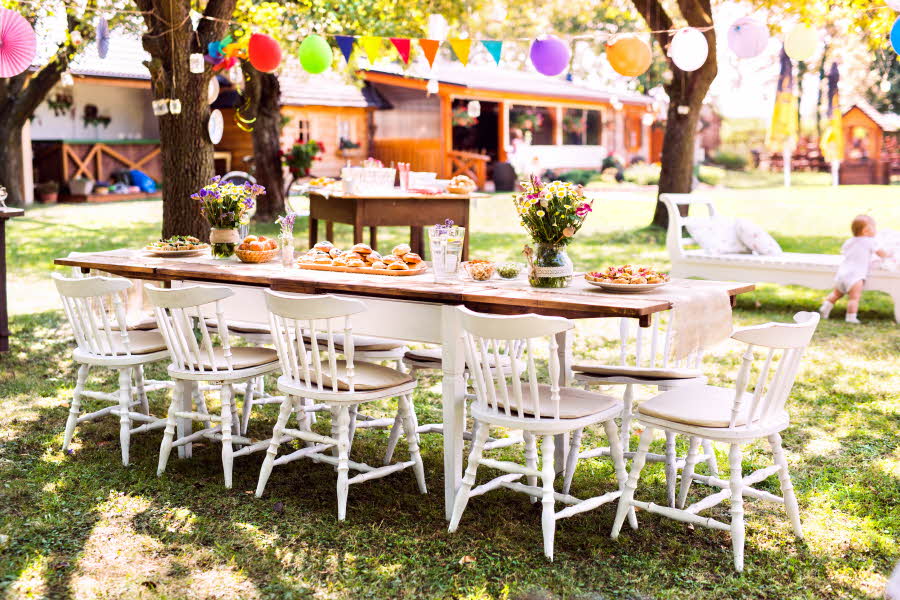 Bord dekket til fest i hagen med ballonger og vimpler
