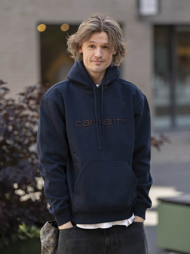 Mann i blå hettegenser, hvit t-skjorte og sorte jeans.