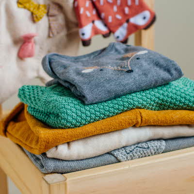 En bunke med barneklær på en stol