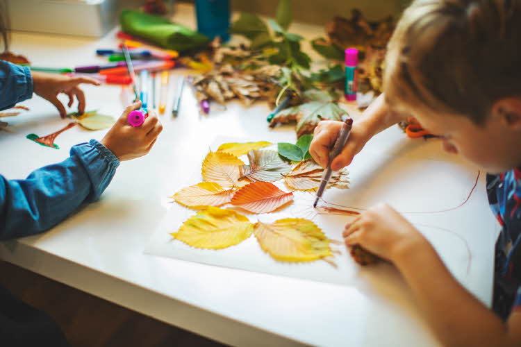 Barn lager bilde med høstblader. Foto.