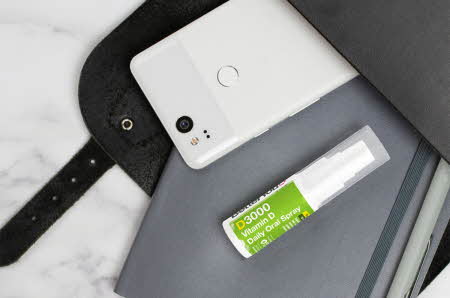 veske med notatbok, mobil og en hvit og grønn spray
