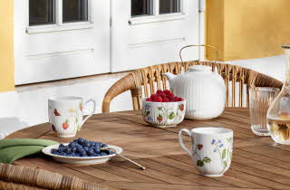 et bord ute som er dekket med kopper og en tekanne, og noen skåler med bær