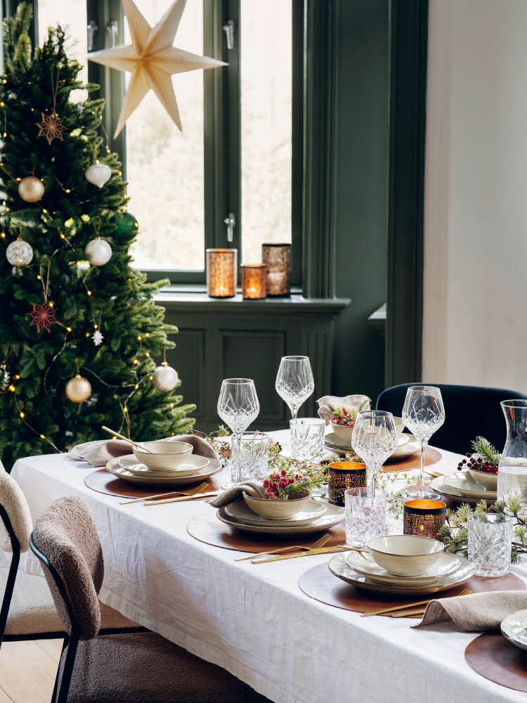 Dekket bord med juletre i bakgrunnen og stjerne i vinduet, produkter fra Kremmerhuset