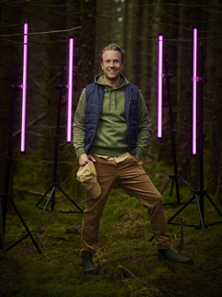 Mann står foran rosa lys i skogen.