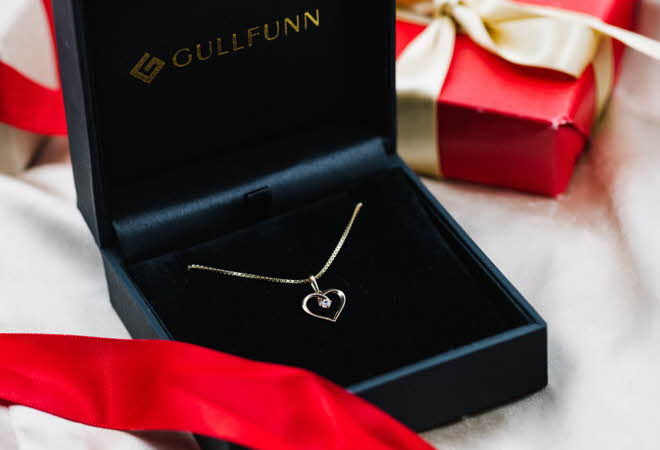 Et gullsmykke med hjerte anheng som ligger i en Gullfunn boks