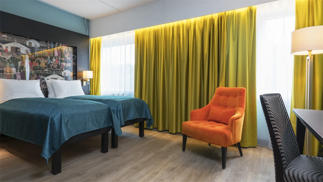 2 senger, en orange lenestol og skrivebord på Thon Hotel Linne