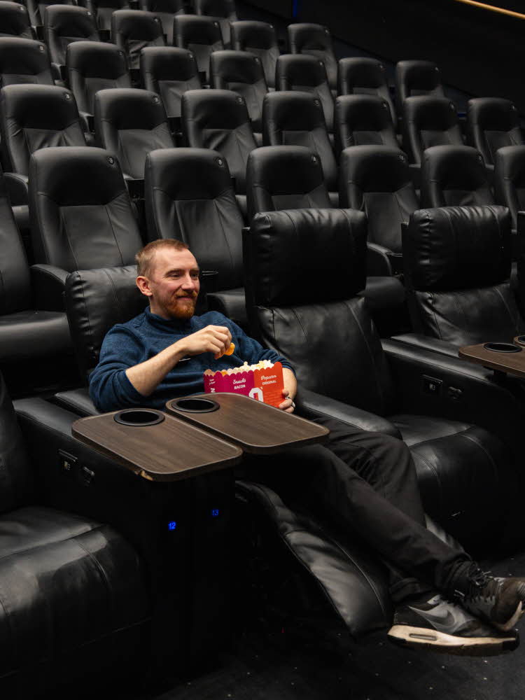 Mann hos ODEON Kino sitter i kinosal med popcorn
