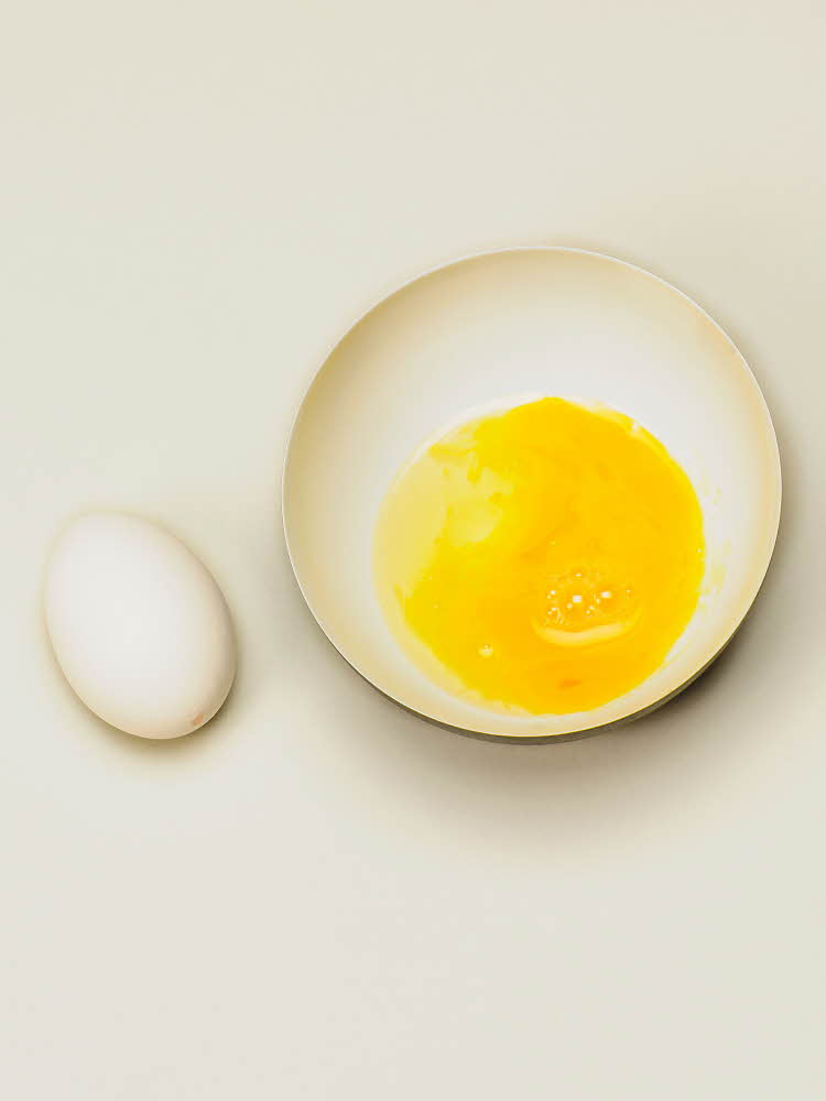 Et egg med en nål i Ett egg og en skål med gul plomme i 