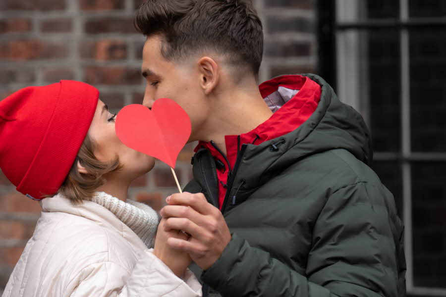 Et par kysser bak et rødt hjerte