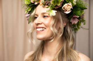 En kvinne med blondt hår og blomsterpynt i håret