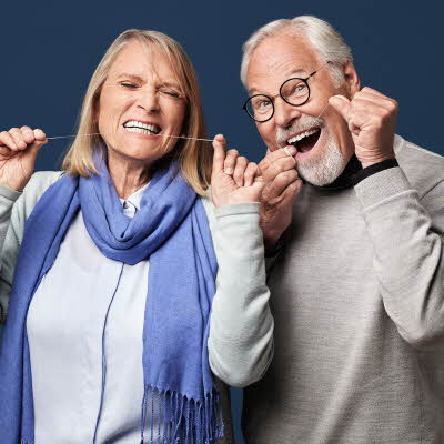 Mann og kvinne som bruker tanntråd