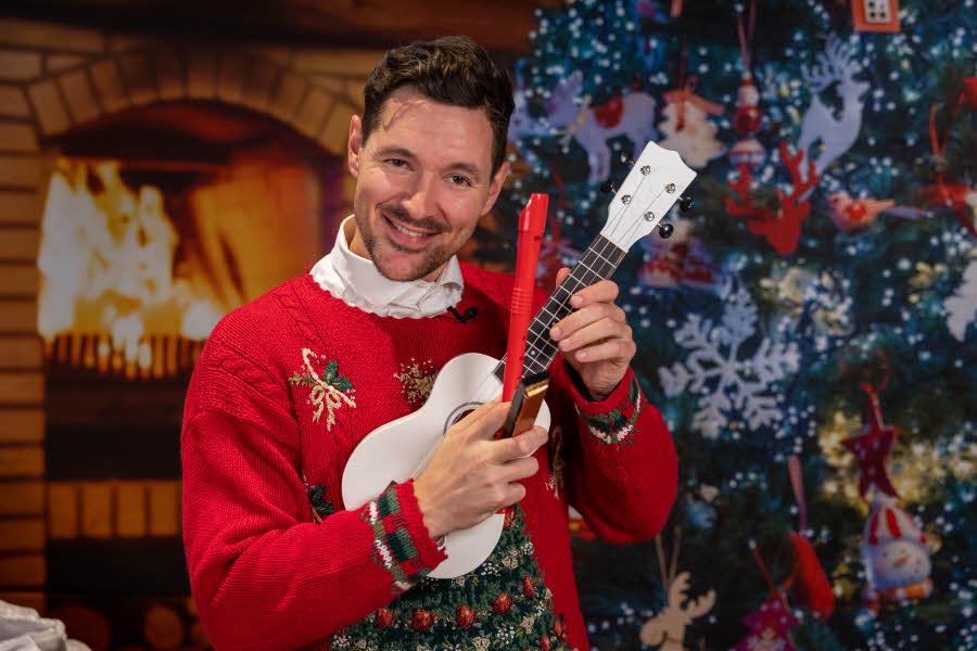 Quizmaster i musikalsk julekalender , Haakon Sørvik smiler og holder frem Blokkfløyte, munnspill og Banjo