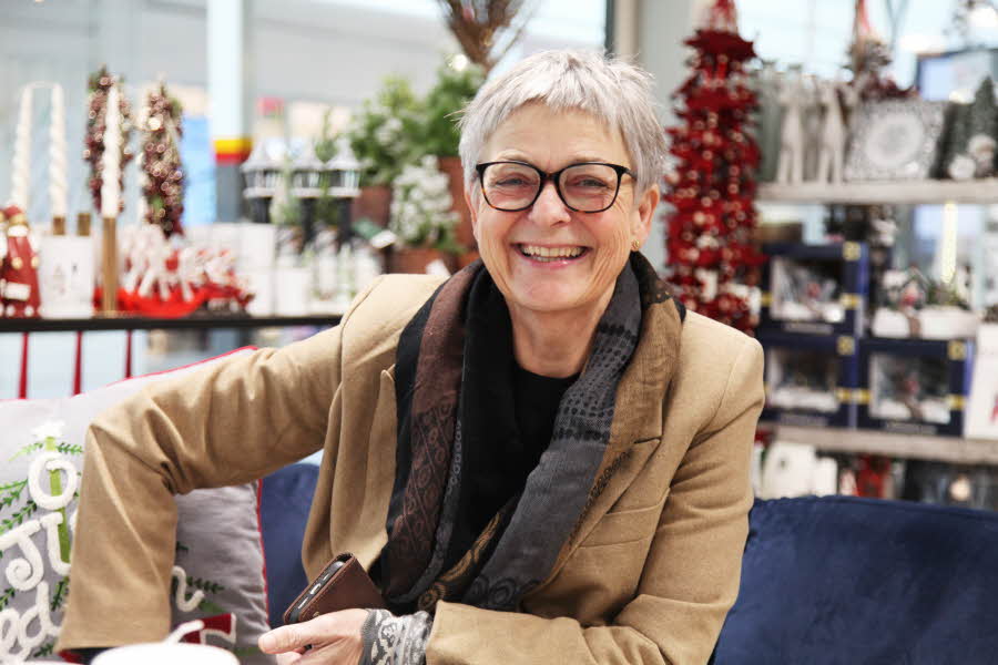 Dame som smiler i julepyntet butikk
