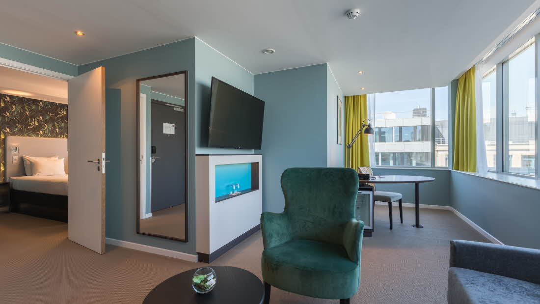Suite hos Thon Hotel EU med soverom, sittegruppe, skrivebord og TV. Gulvet er teppebelagt.
