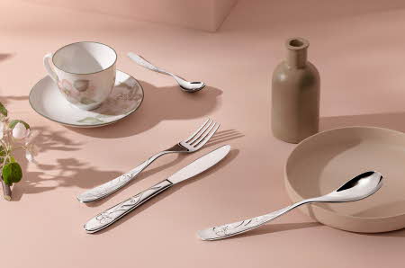 Bestikk ligger rundt en kopp og en skål og en karaffel.