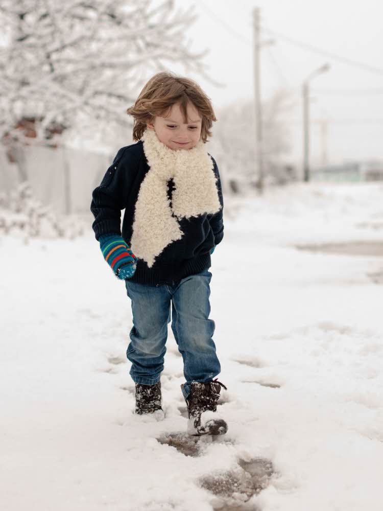 Liten gutt går på snø 