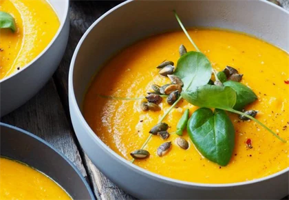 Nærbilde av skåler med gresskarsuppe pyntet med basilikum
