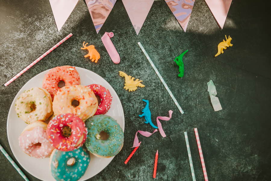 Fat med fargerike donuts og pynt liggende rundt. Illustrasjonsfoto til artikkel om kaker til babyshower.