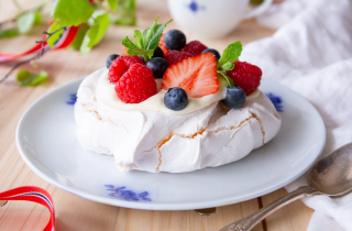 En asjett med pavlova kake med krem, blåbær og jordbær