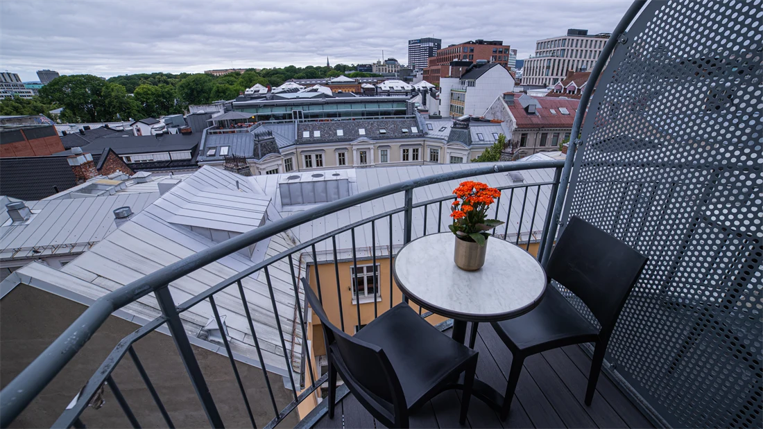 Balkong med utsikt, to stoler og lite rundt bord 